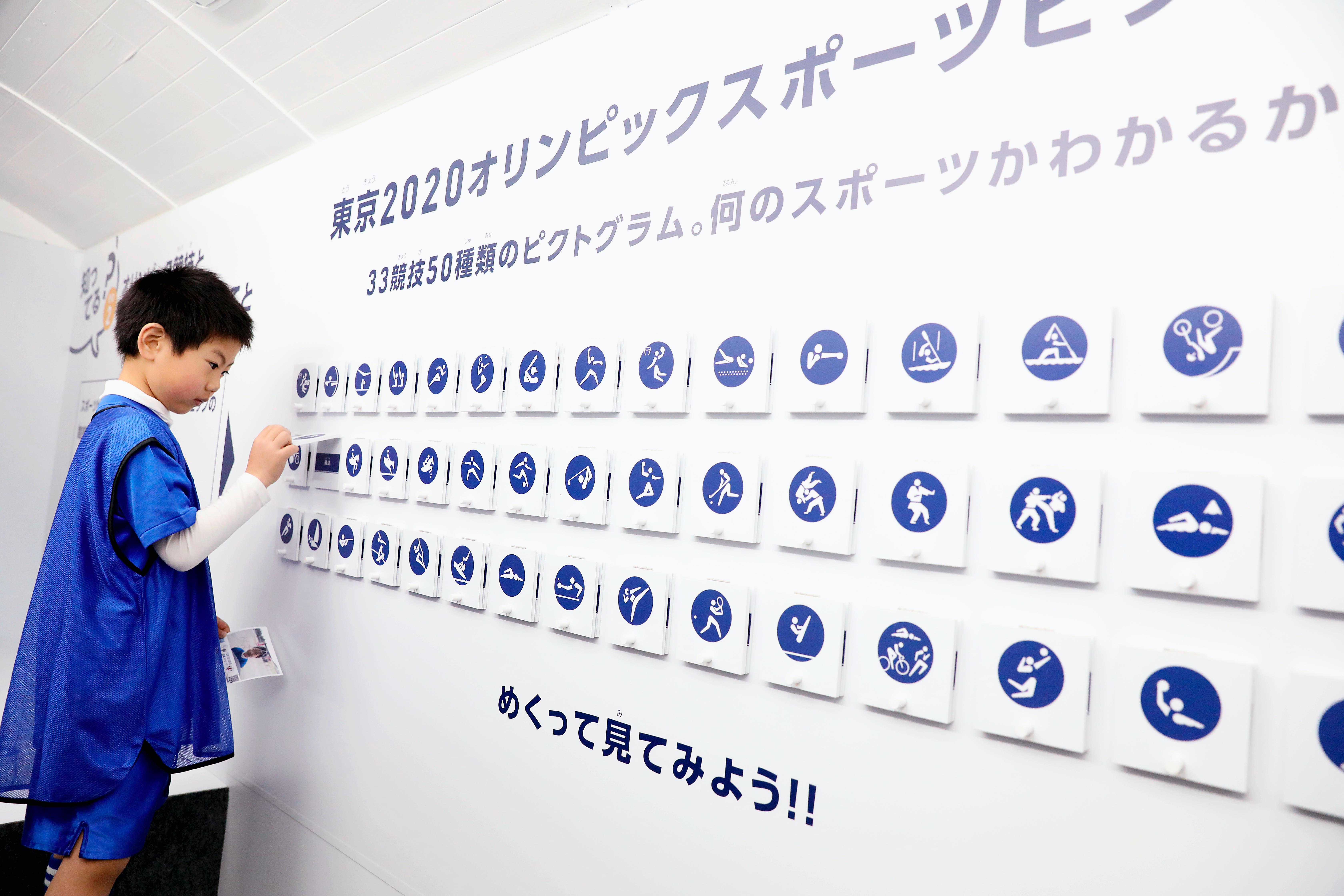 Un enfant regarde une affiche des pictogrammes des Jeux de Tokyo